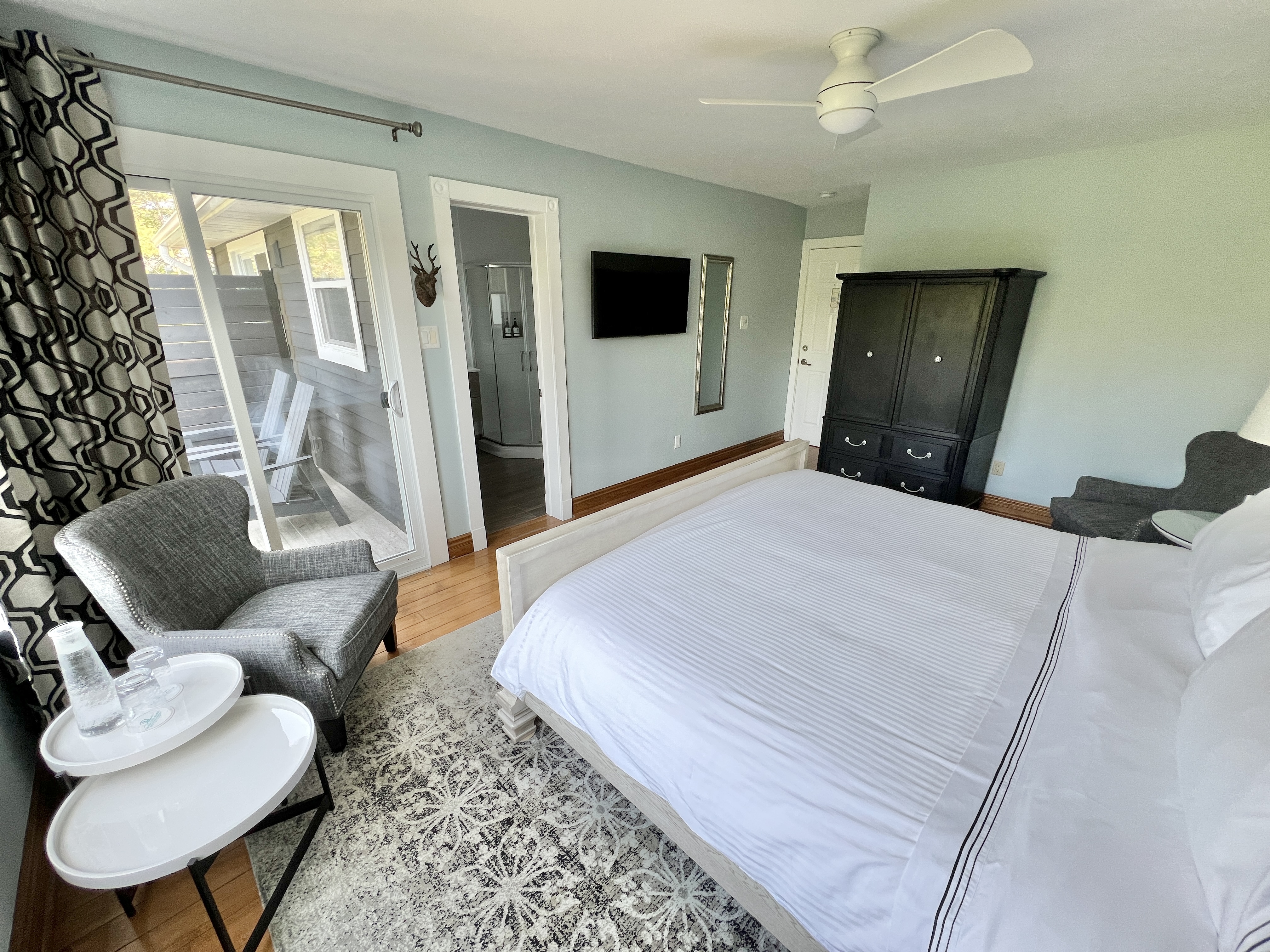 An open door reveals a bedroom with a bed and ottoman, a chair, and a window with curtains. The door handle and doorknob are visible, along with a key in the lock.