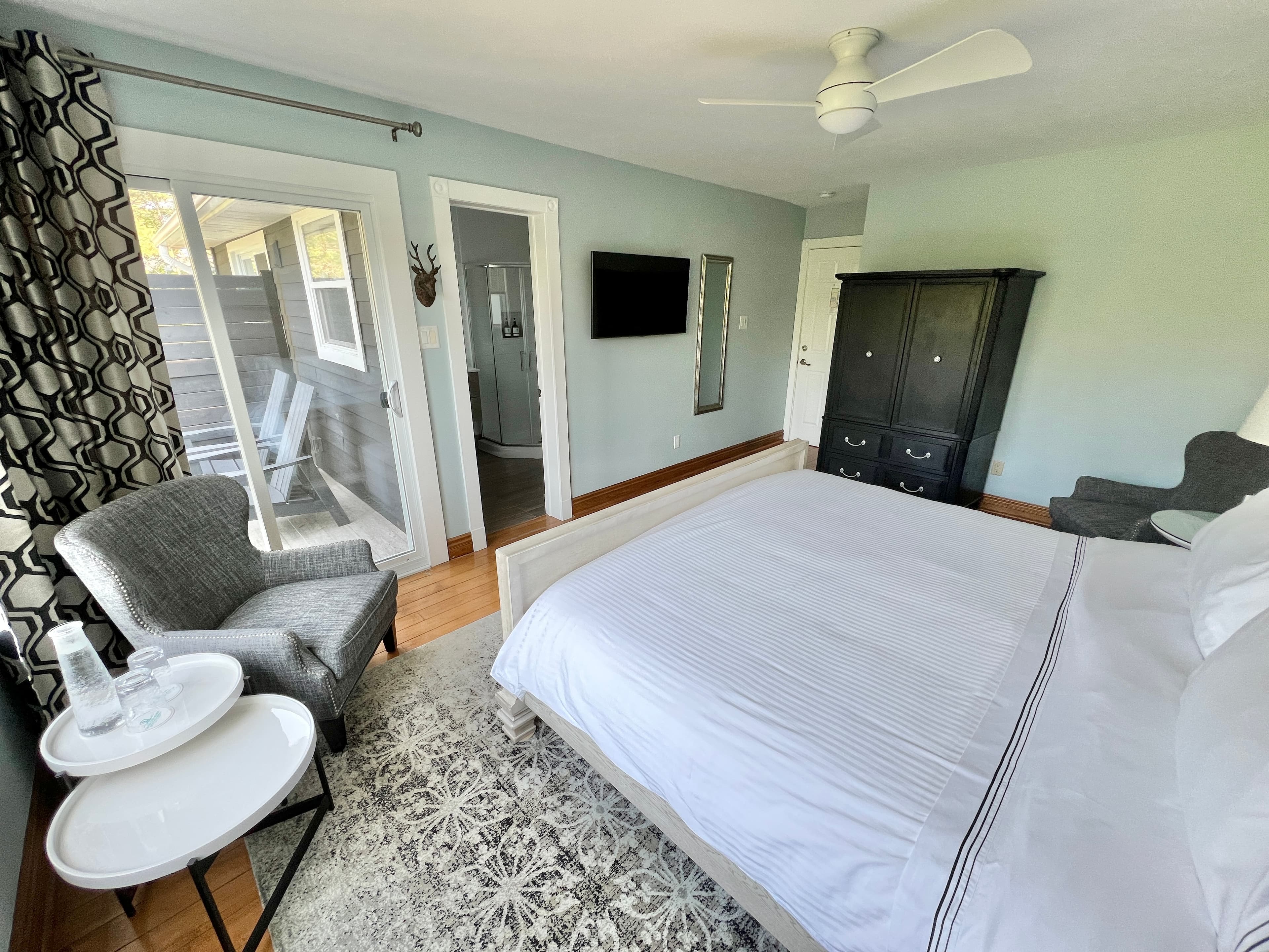 An open door reveals a bedroom with a bed and ottoman, a chair, and a window with curtains. The door handle and doorknob are visible, along with a key in the lock.