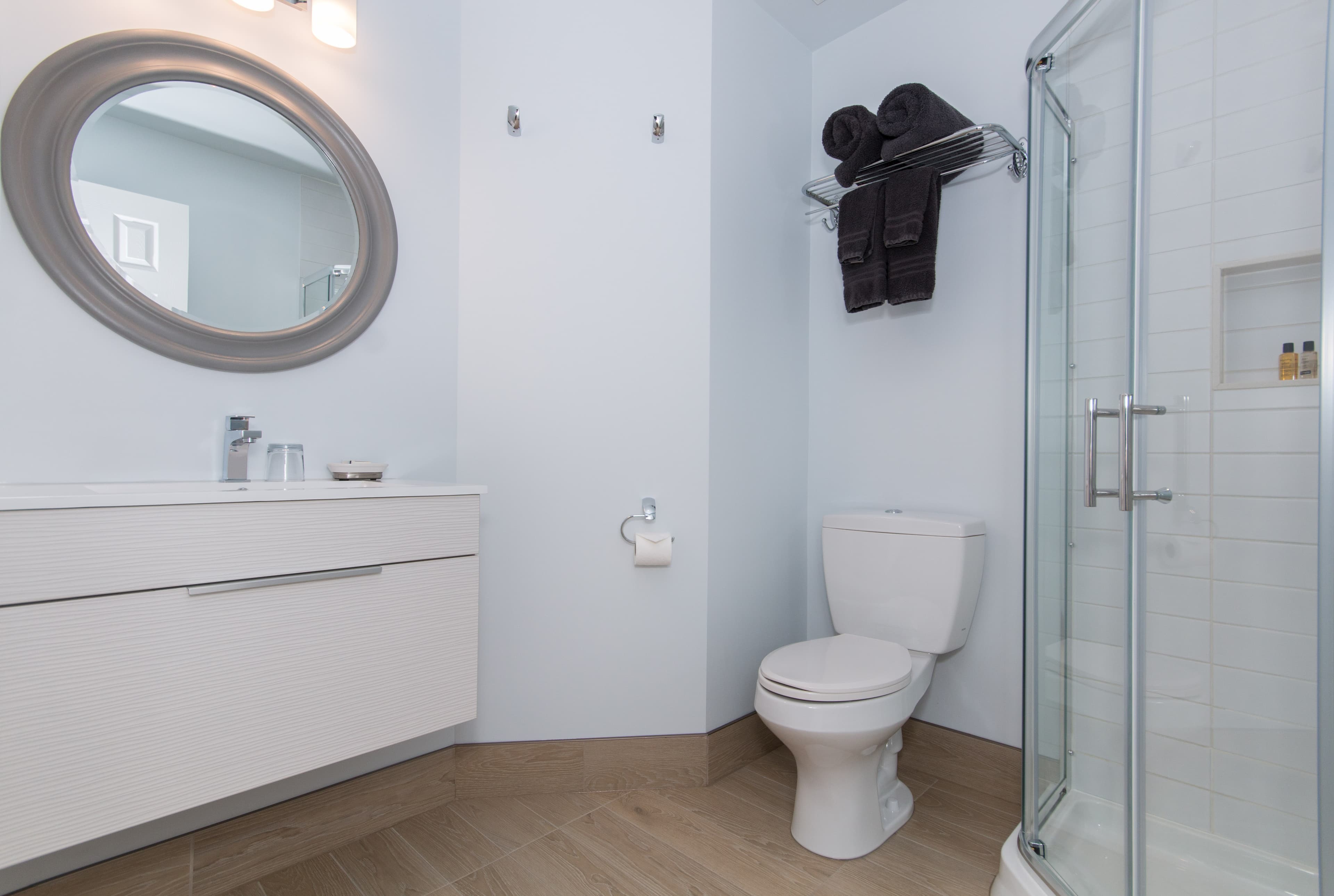 A pristine white bathroom with vanity, sink toilet, and glass-enclosed shower.