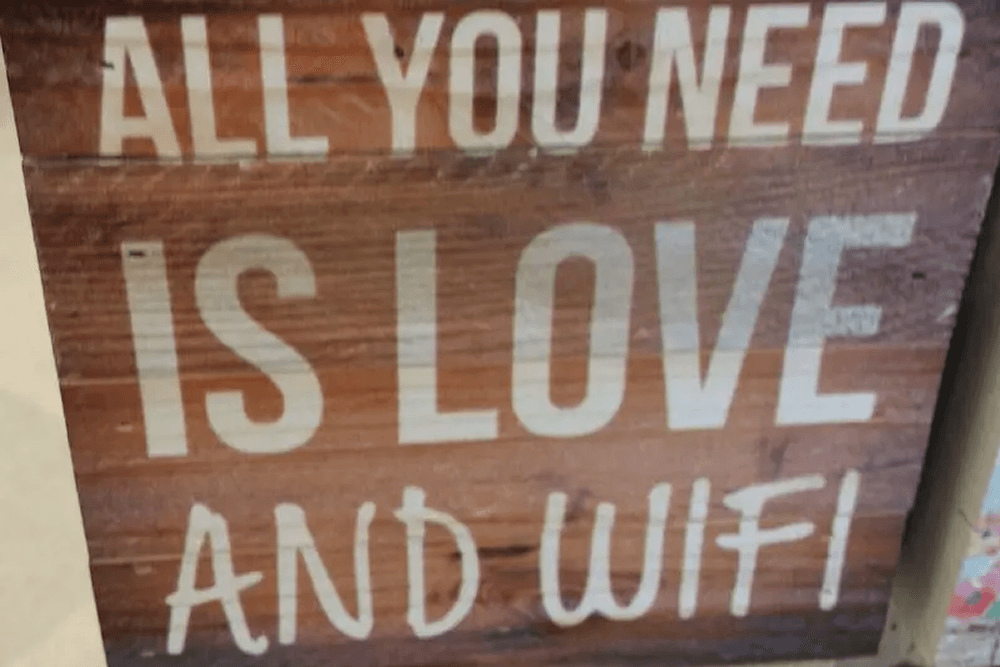 Wood sign that says "all you need is love and wifi"