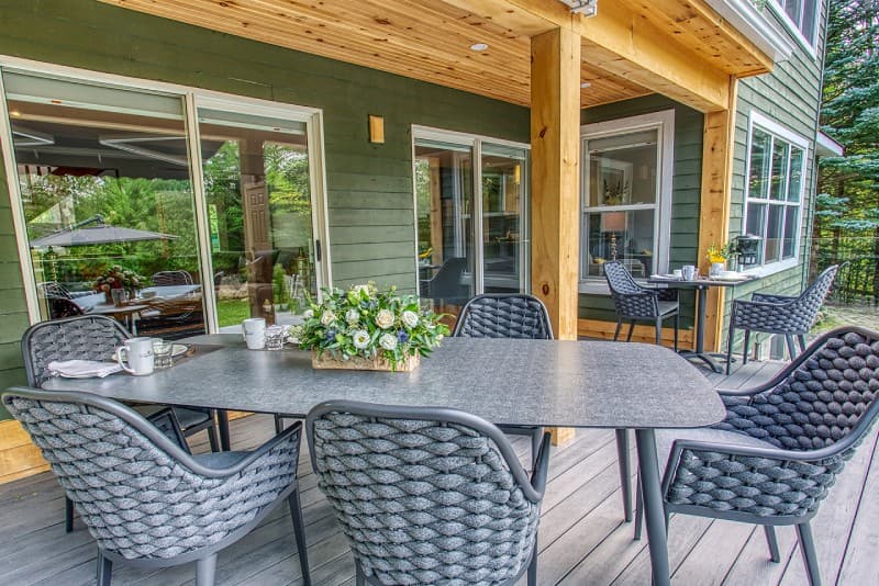 Horizontal patio table with flowers as centerpiece in front of Manor with view of wood posts and sliding glass doors