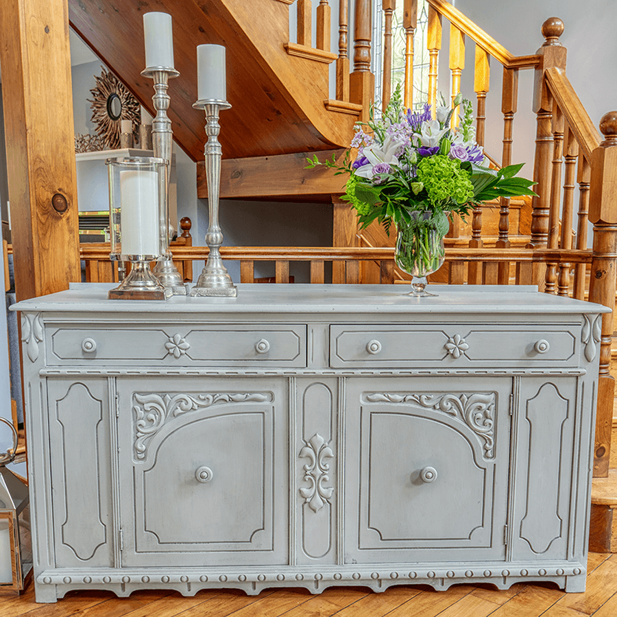 Gray foyer table with doors in front of grand staircase in oak