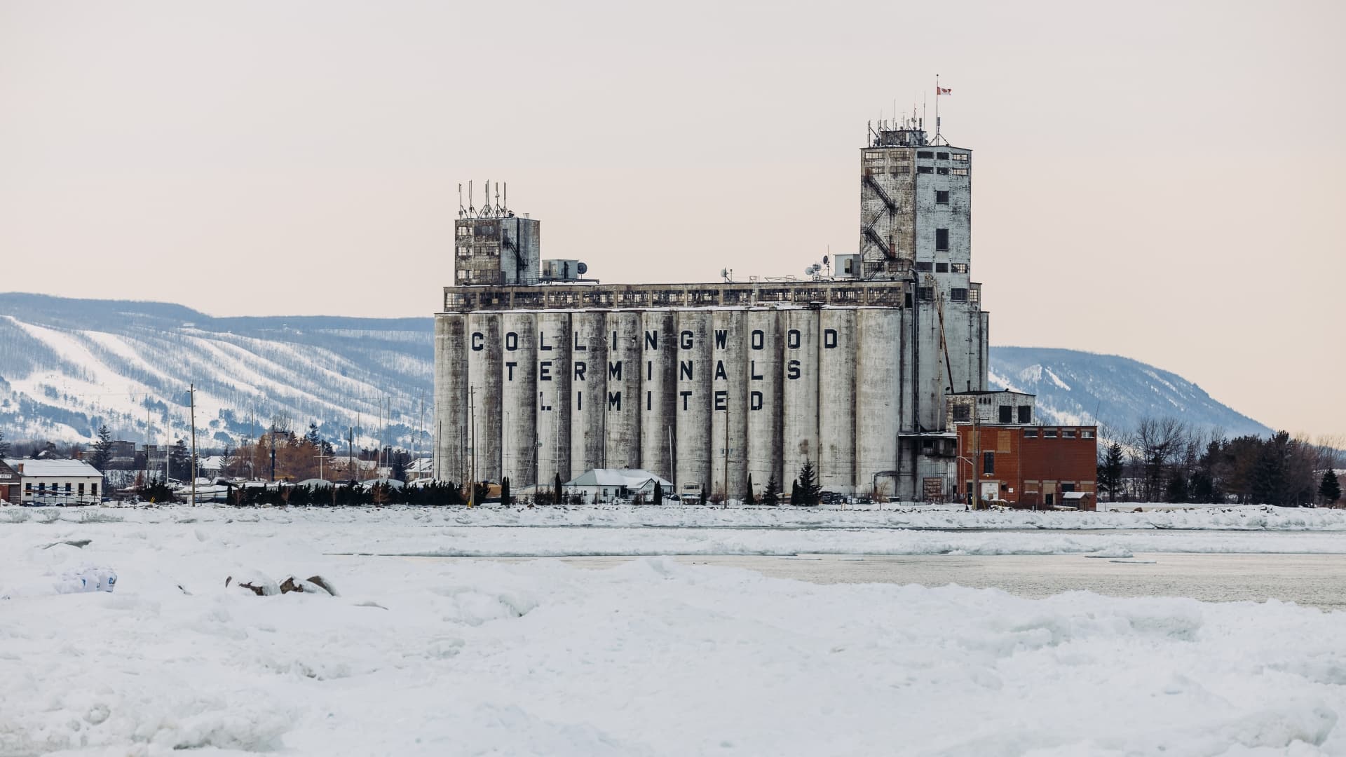 A concrete grain elevator labeled "Collingwood Terminals Limited" stands amid a snowy landscape.