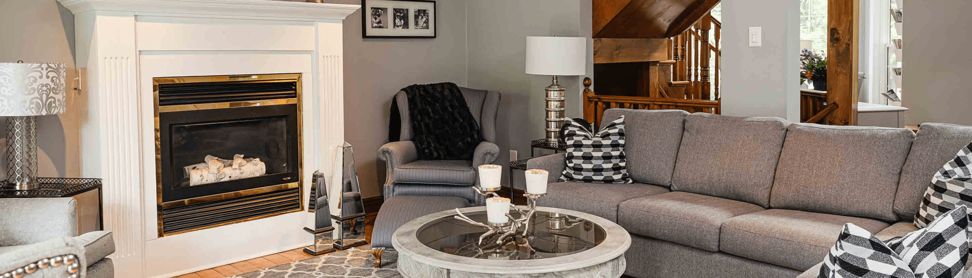 Cozy living room featuring a sofa, armchair, coffee table, lamp, and a fireplace.
