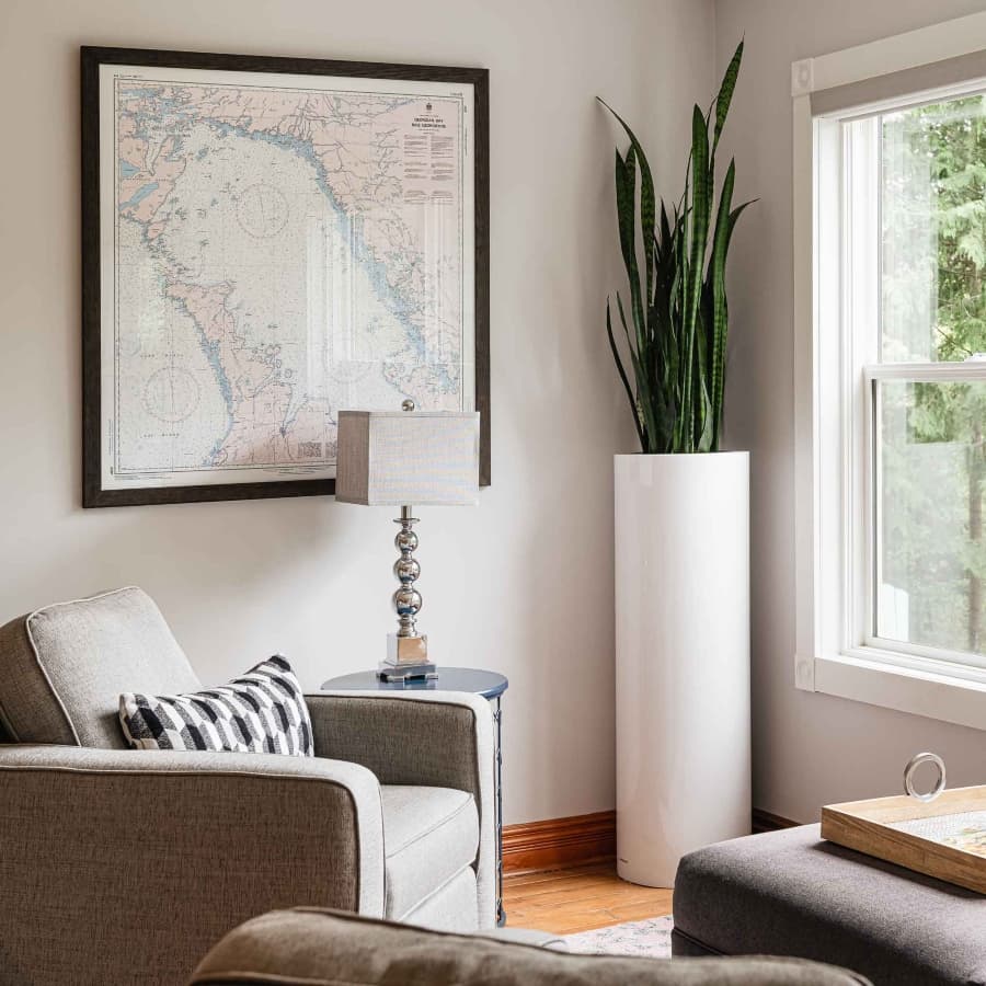 A cozy living space featuring a map on the wall, a lamp, a potted plant, and comfortable seating.