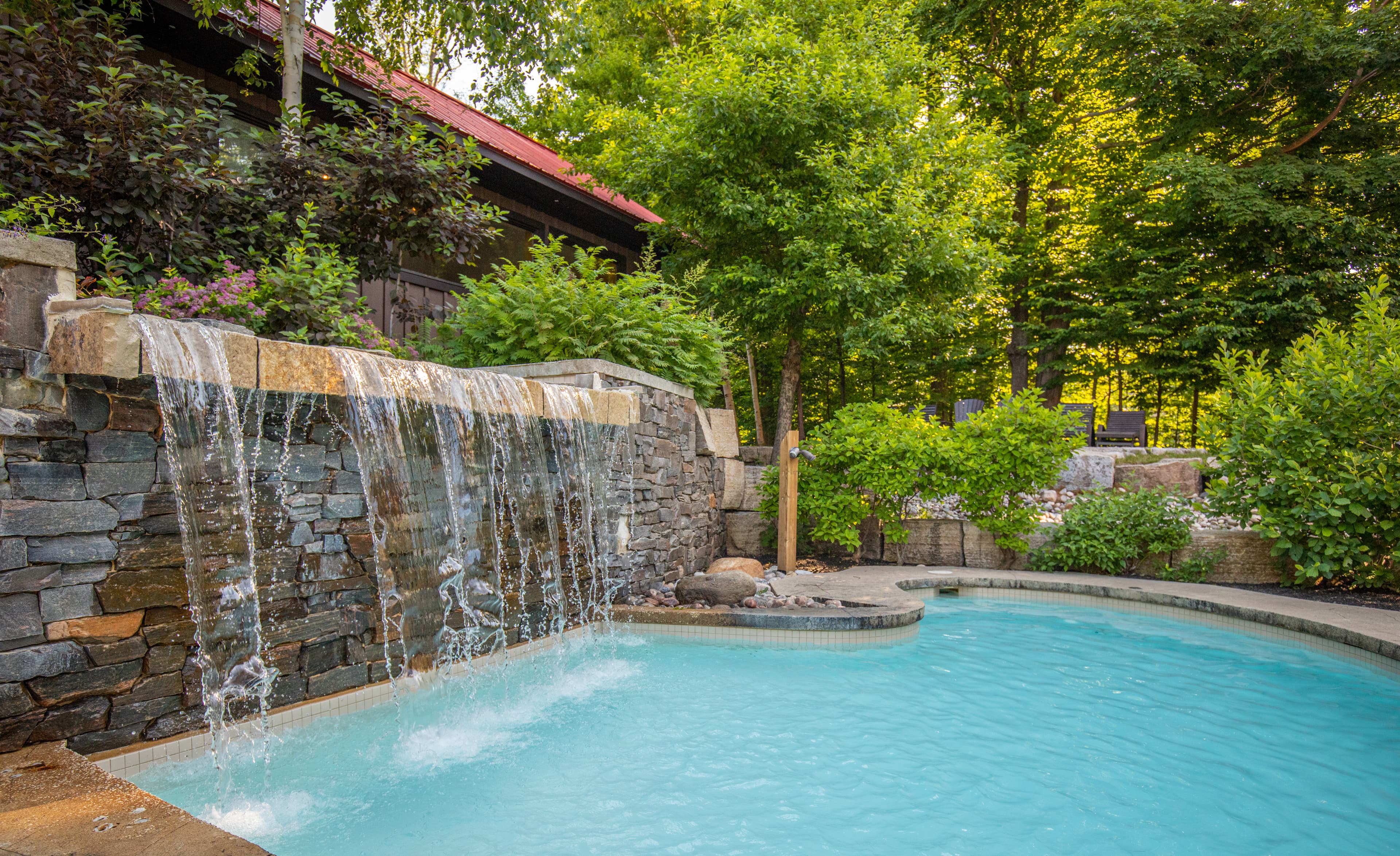 A tranquil pool with a stone waterfall surrounded by lush greenery.
