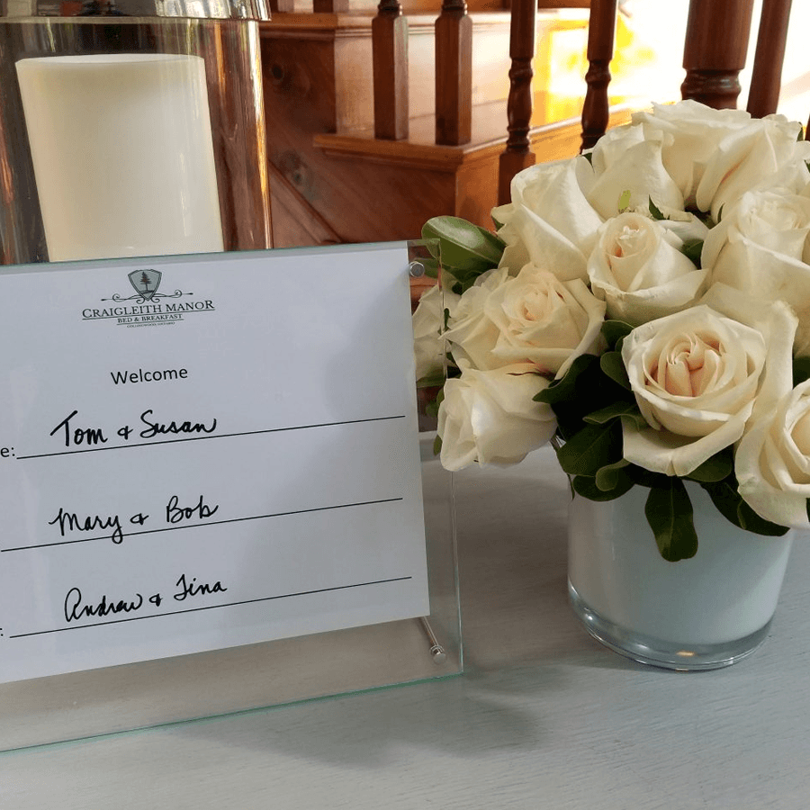 Welcome placard on foyer table with white roses personally welcoming new guests