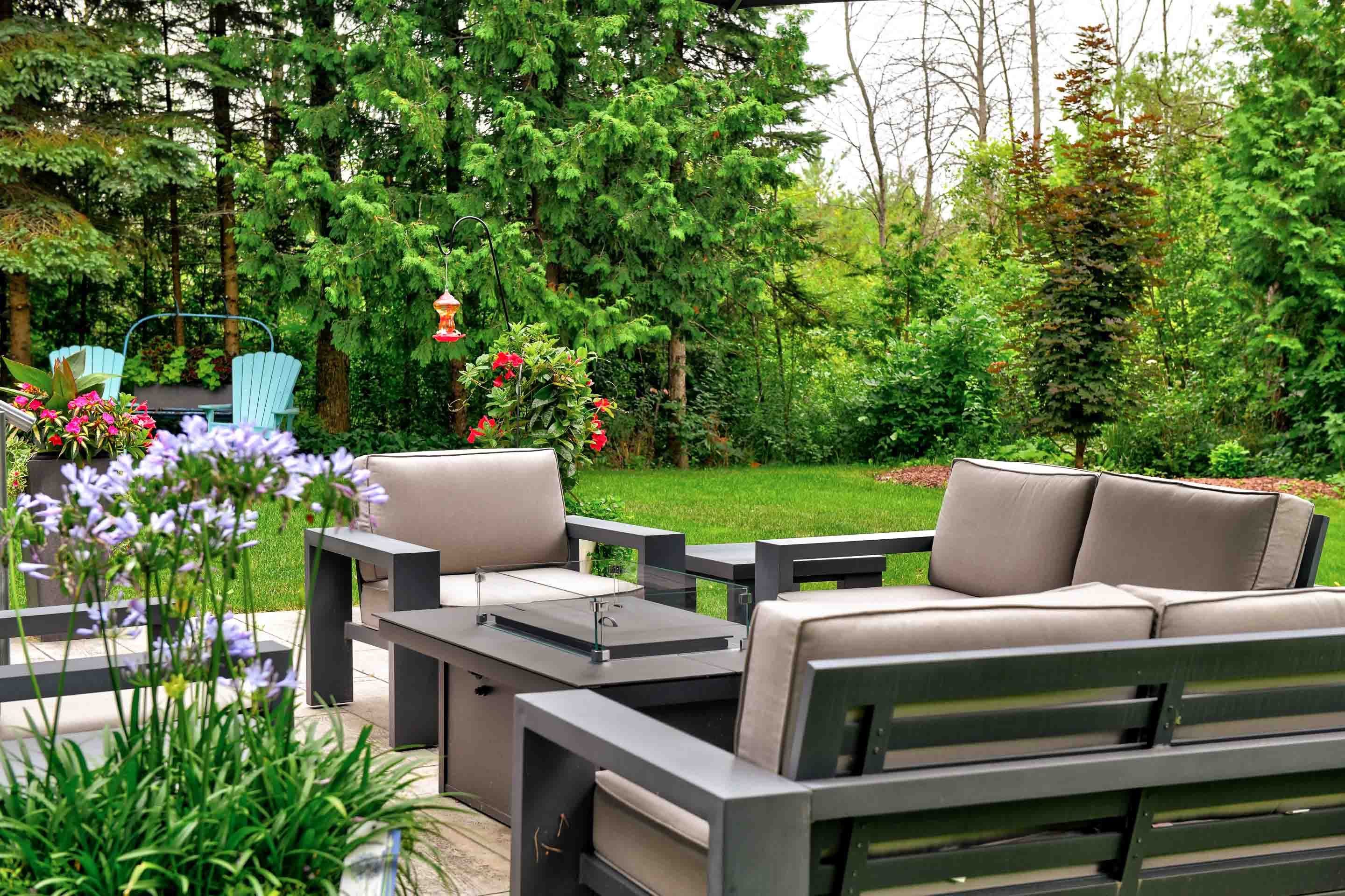 A cozy outdoor seating area surrounded by lush greenery and colorful flowers.