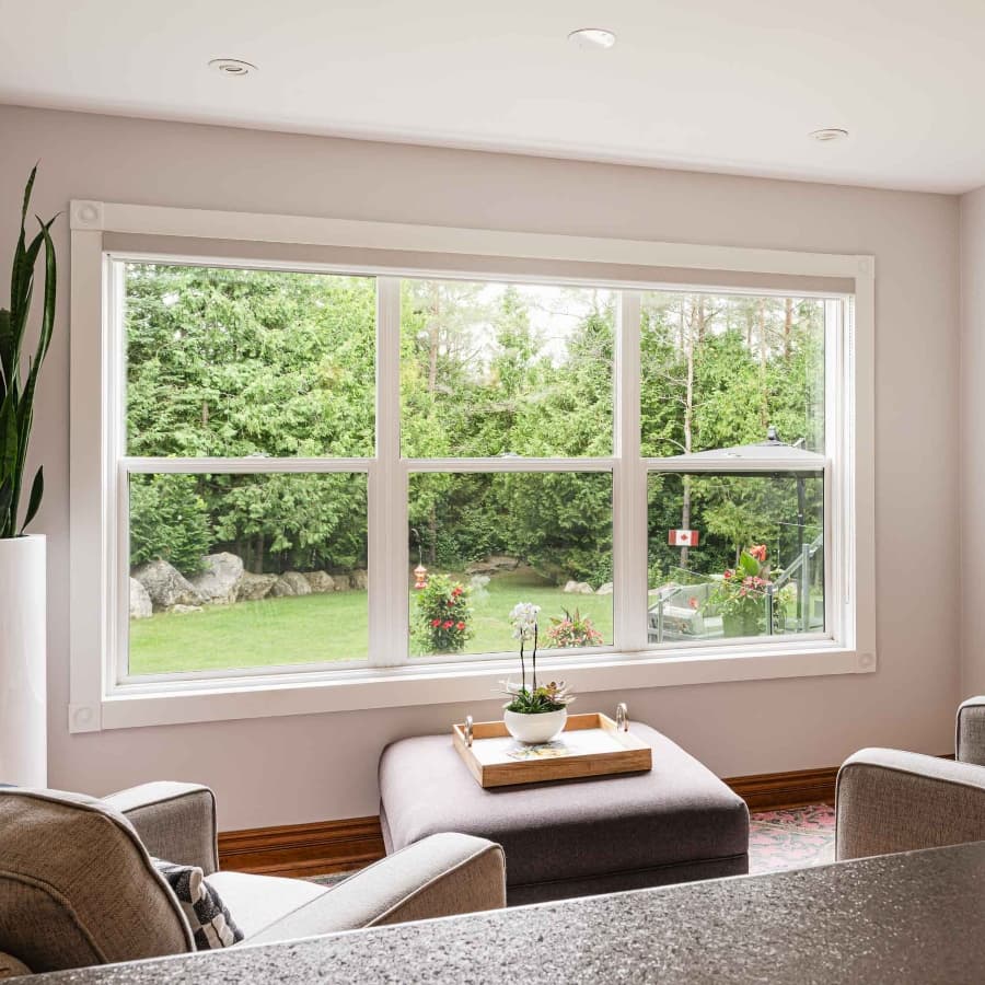 Bright living room with a large window overlooking a lush, green yard and decorative flowers.