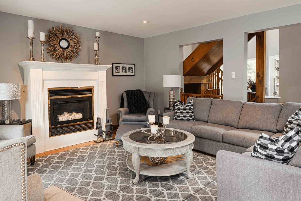 Cozy living room featuring a fireplace, gray furniture, and a patterned rug.